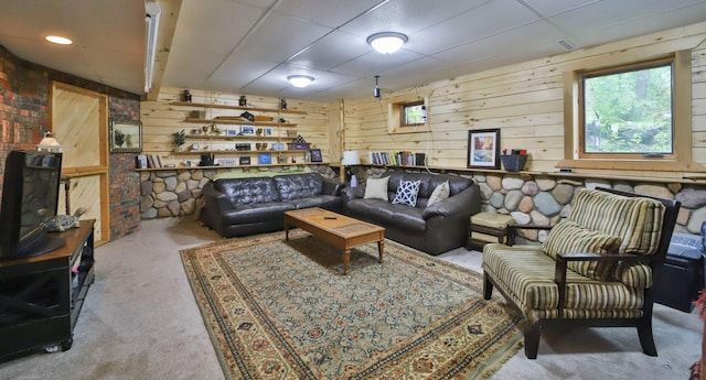 carpeted living room featuring wood walls, a wealth of natural light, and a drop ceiling