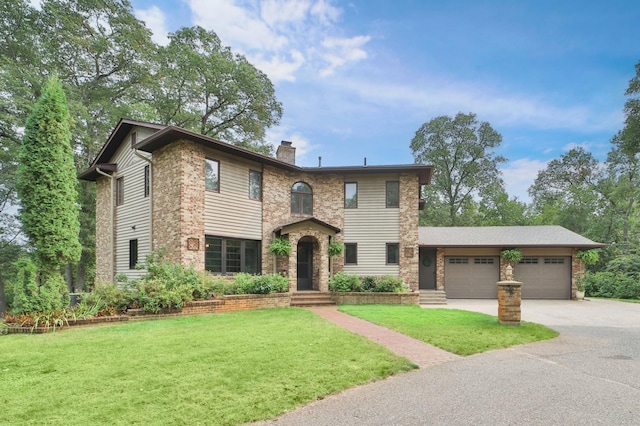 view of front facade with a garage, a chimney, a front lawn, and driveway