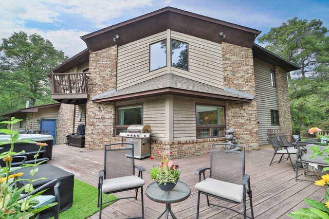 back of house featuring a wooden deck, outdoor dining space, brick siding, and a hot tub
