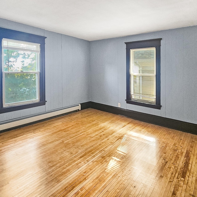 unfurnished room with a baseboard radiator and light hardwood / wood-style flooring