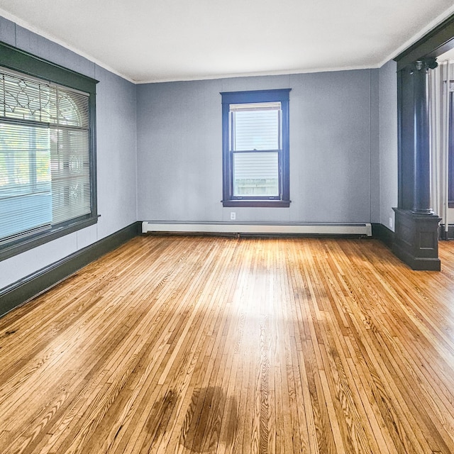 spare room featuring a baseboard heating unit, ornamental molding, and light hardwood / wood-style flooring