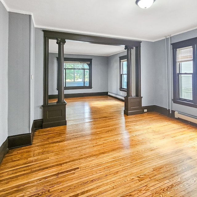 unfurnished living room featuring light hardwood / wood-style floors, ornamental molding, and a baseboard heating unit