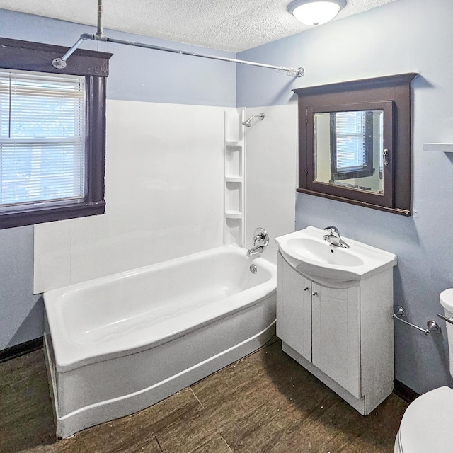 full bathroom with hardwood / wood-style floors,  shower combination, a textured ceiling, toilet, and vanity