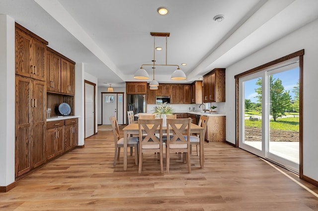 dining room with a raised ceiling, light hardwood / wood-style flooring, and sink