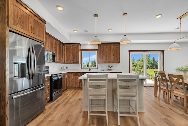 kitchen with a wealth of natural light, pendant lighting, and appliances with stainless steel finishes