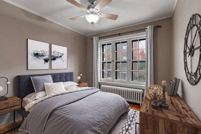 bedroom featuring radiator, ceiling fan, crown molding, and wood-type flooring