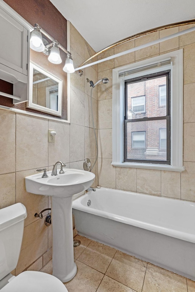 bathroom featuring tiled shower / bath, tile walls, toilet, and tile patterned floors