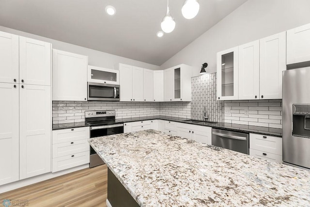 kitchen with lofted ceiling, decorative backsplash, hanging light fixtures, sink, and stainless steel appliances