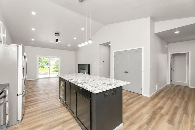 kitchen with lofted ceiling, a kitchen island, light wood-type flooring, pendant lighting, and stainless steel appliances