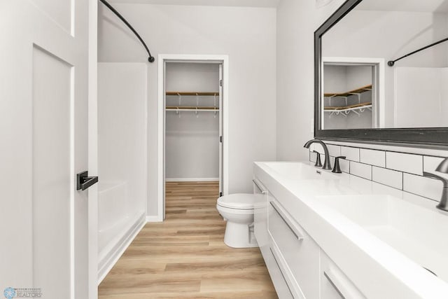 bathroom featuring backsplash, hardwood / wood-style floors, toilet, vanity, and a shower