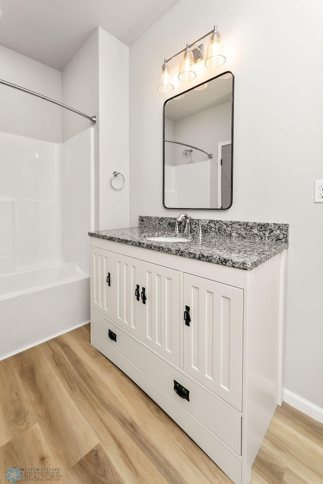 bathroom with vanity, washtub / shower combination, and hardwood / wood-style flooring