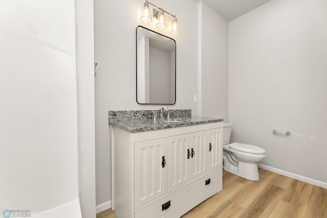 bathroom with toilet, hardwood / wood-style floors, and vanity