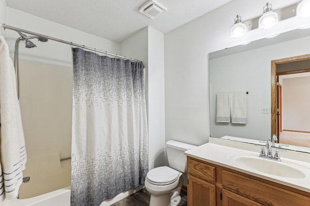 full bathroom featuring toilet, hardwood / wood-style floors, shower / tub combo with curtain, a textured ceiling, and vanity