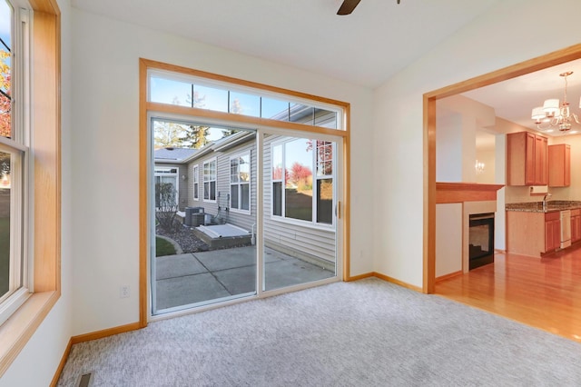 interior space with light carpet, lofted ceiling, and ceiling fan with notable chandelier