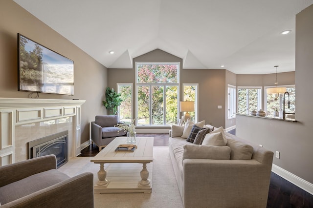 living room featuring hardwood / wood-style floors, vaulted ceiling, and a tiled fireplace