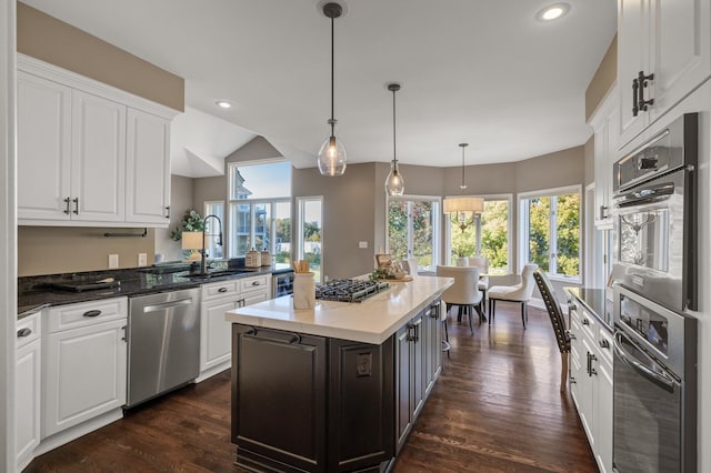 kitchen with white cabinetry, stainless steel appliances, dark hardwood / wood-style flooring, and hanging light fixtures