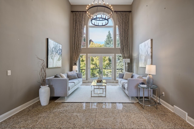 living room featuring french doors, a chandelier, and a high ceiling