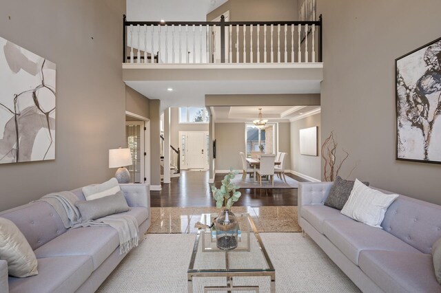 living room featuring crown molding, hardwood / wood-style floors, a chandelier, and a high ceiling