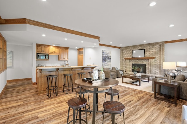 dining space with crown molding, light hardwood / wood-style flooring, and a brick fireplace