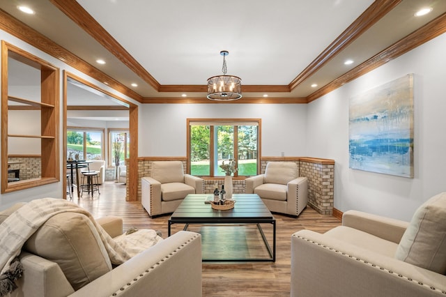 living room featuring a notable chandelier, light wood-type flooring, and crown molding