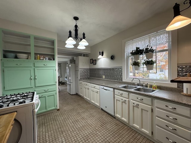 kitchen featuring sink, white cabinetry, white appliances, and decorative light fixtures