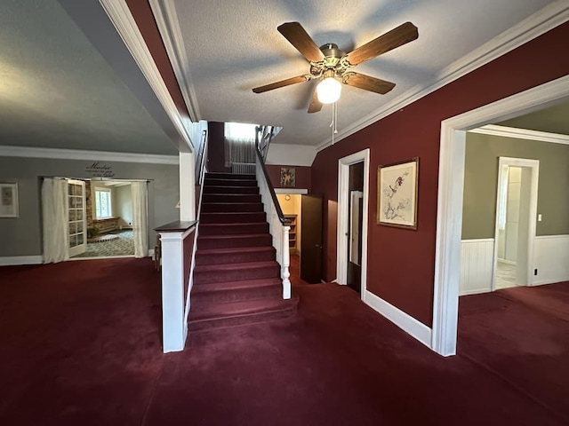 stairway with carpet floors, a textured ceiling, ornamental molding, and ceiling fan