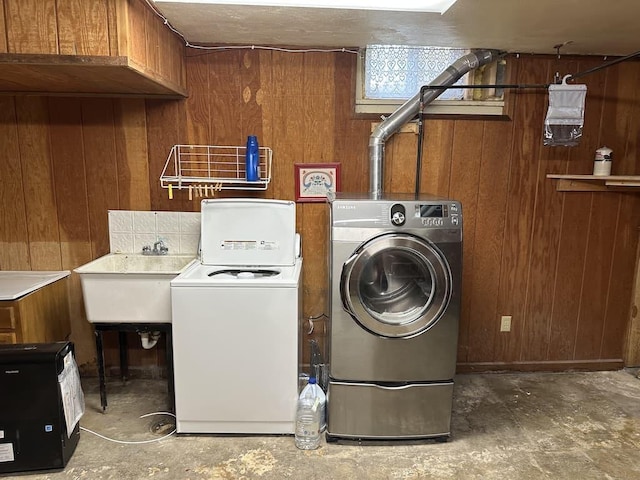 washroom featuring sink, wood walls, and independent washer and dryer