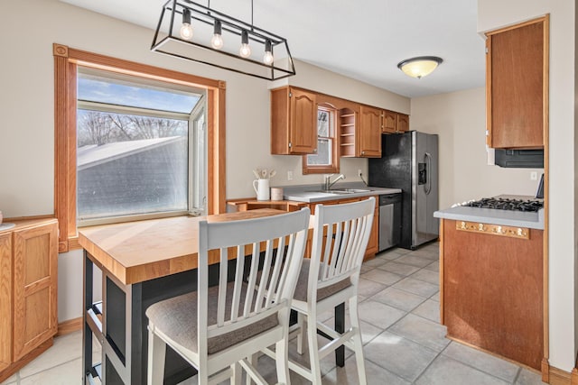 kitchen with pendant lighting, stainless steel appliances, light tile patterned flooring, and a wealth of natural light