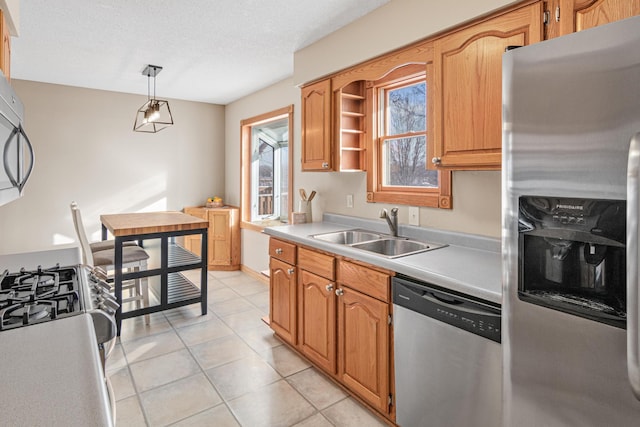 kitchen with light tile patterned flooring, sink, a textured ceiling, appliances with stainless steel finishes, and pendant lighting