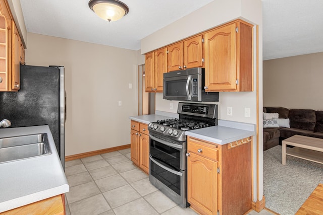 kitchen with sink, light tile patterned flooring, and appliances with stainless steel finishes