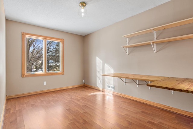 spare room with a textured ceiling and light hardwood / wood-style floors