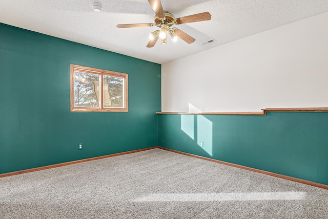 carpeted empty room with ceiling fan and a textured ceiling