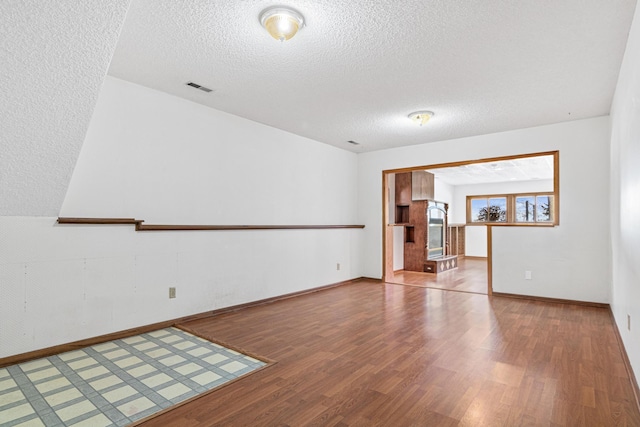 unfurnished room with hardwood / wood-style flooring and a textured ceiling