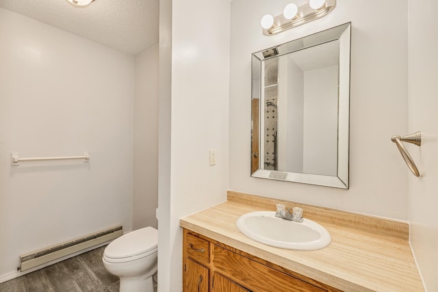 bathroom featuring toilet, wood-type flooring, baseboard heating, vanity, and a textured ceiling