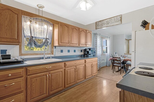 3234 14th Ave, Owatonna, MN 55060 - kitchen featuring a sink, white appliances, dark countertops, light wood-style flooring, and brown cabinetry