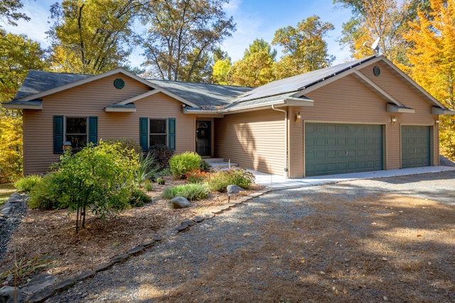 single story home featuring driveway, an attached garage, and roof mounted solar panels