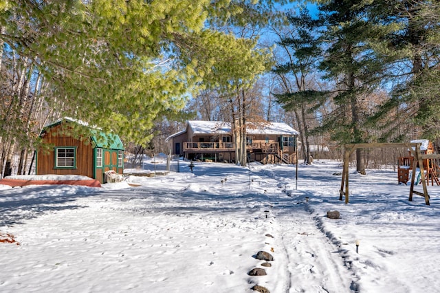 yard layered in snow with an outbuilding and a wooden deck