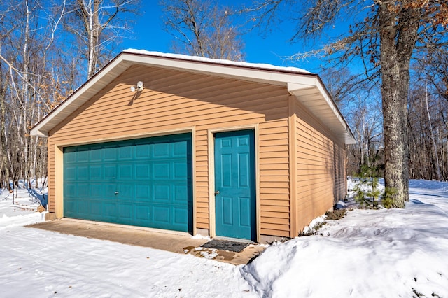 snow covered garage featuring a detached garage