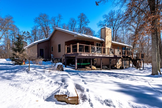 snow covered property with a chimney and a wooden deck