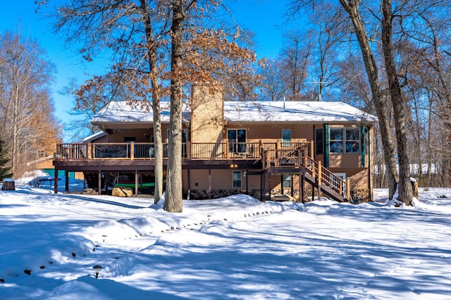 snow covered rear of property with stairs and a deck