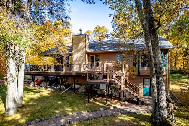 back of property featuring a chimney, a lawn, a deck, and stairs