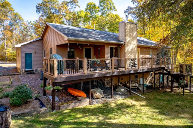 rear view of house with a chimney, a deck, and a yard