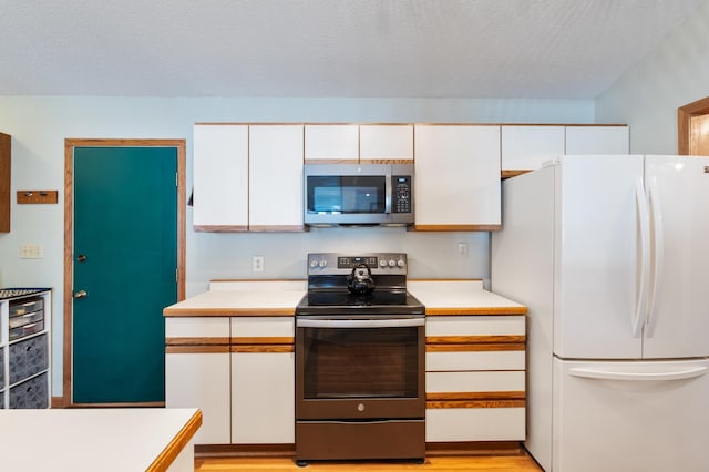 kitchen featuring stainless steel appliances, light countertops, and white cabinetry