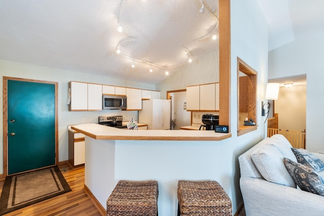 kitchen featuring light wood finished floors, stainless steel appliances, light countertops, white cabinetry, and a peninsula