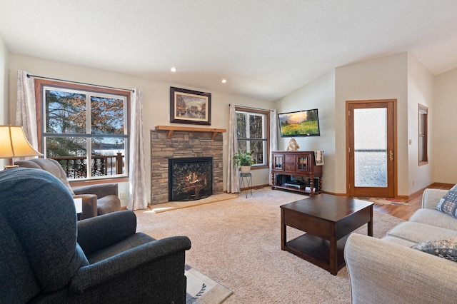 living area featuring light colored carpet, baseboards, vaulted ceiling, and a stone fireplace