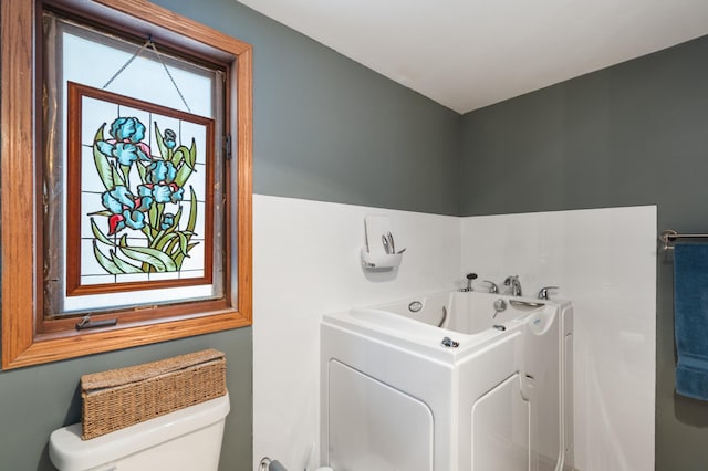 full bath featuring toilet and a whirlpool tub