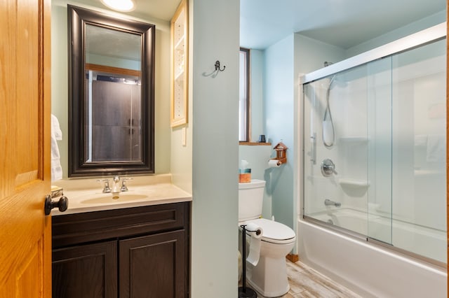 bathroom with enclosed tub / shower combo, wood finished floors, vanity, and toilet