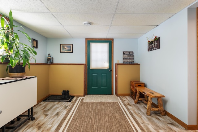 foyer featuring light wood-type flooring, a paneled ceiling, and baseboards