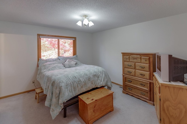 bedroom with light colored carpet and a textured ceiling