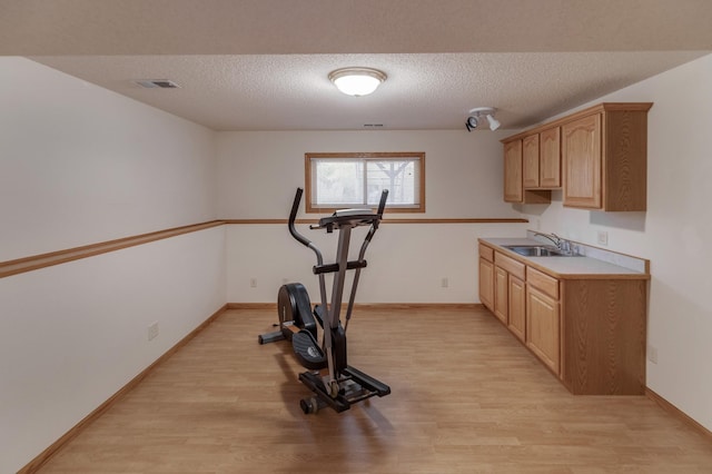 workout area featuring a textured ceiling, light hardwood / wood-style floors, and sink